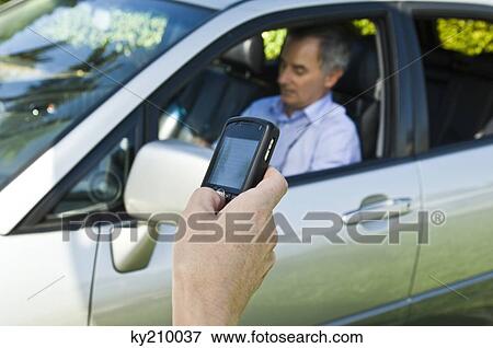 Person's hand text messaging and a man sitting in a car in the background View Large Photo Image Stock Photo - Person's hand text messaging and a man sitting in a car in the background. Fotosearch