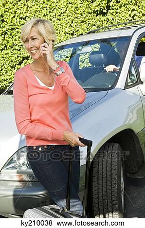 Woman holding a luggage and talking on a mobile phone View Large Photo Image Stock Photo - Woman holding a luggage and talking on a mobile phone. Fotosearch