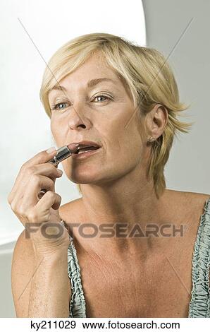 Close-up of a woman applying lipstick on her lips View Large Photo Image Stock Photo - Close-up of a woman applying lipstick on her lips. Fotosearch