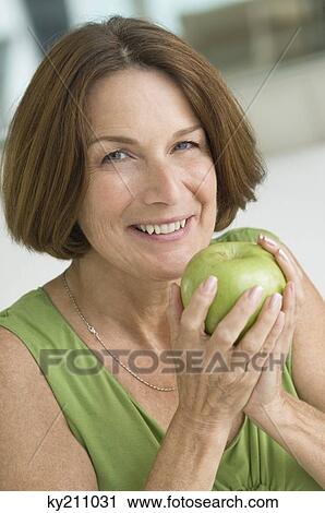 Portrait of a woman eating an apple View Large Photo Image Stock Image - Portrait of a woman eating an apple. Fotosearch