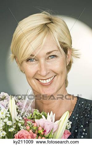 Portrait of a woman smiling with a bouquet of flowers View Large Photo Image Stock Photo - Portrait of a woman smiling with a bouquet of flowers. Fotosearch