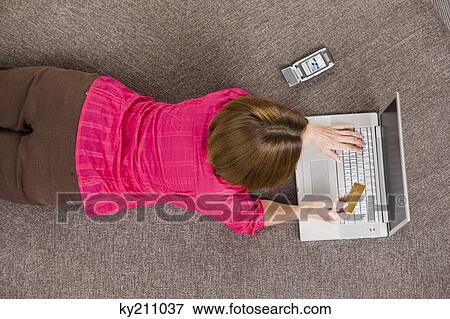 Stock Photo - Woman holding a credit card and working on a laptop. Fotosearch