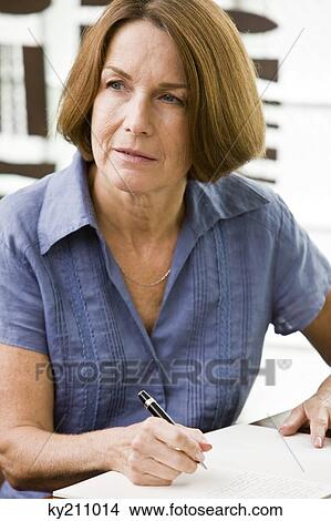 Woman holding a pen and thinking View Large Photo Image Picture - Woman holding a pen and thinking. Fotosearch
