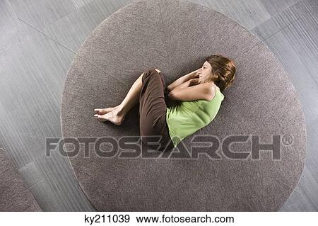 Woman lying on a round sofa View Large Photo Image Stock Photo - Woman lying on a round sofa. Fotosearch
