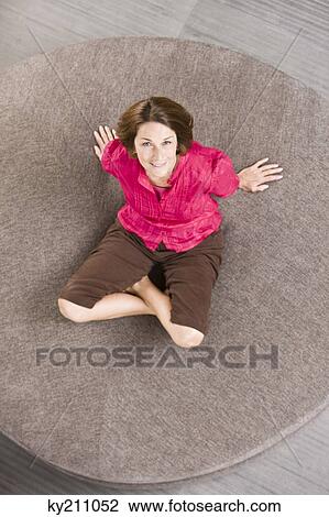 Woman sitting on a round sofa and smiling View Large Photo Image Stock Image - Woman sitting on a round sofa and smiling. Fotosearch