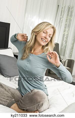 Woman stretching in bed and smiling View Large Photo Image Stock Image - Woman stretching in bed and smiling. Fotosearch