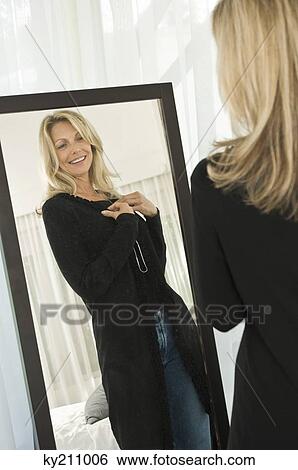Woman trying on a dress in front of a mirror View Large Photo Image Stock Photograph - Woman trying on a dress in front of a mirror. Fotosearch