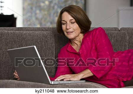 Woman working on a laptop and smiling View Large Photo Image Stock Photo - Woman working on a laptop and smiling. Fotosearch