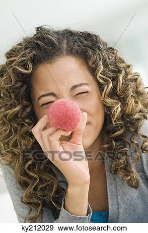 Stock Photo - Close-up of a girl holding a blush brush in front of her face. Fotosearch