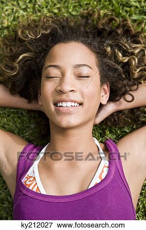 Close-up of a girl lying on grass View Large Photo Image Stock Photo - Close-up of a girl lying on grass. Fotosearch