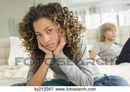 Girl sitting on the bed with a teenage boy reclining View Large Photo Image Stock Photo - Girl sitting on the bed with a teenage boy reclining. Fotosearch