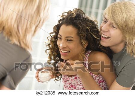 Stock Photography - Teenage boy applying moisturizer on a girl's face. Fotosearch