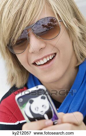 Stock Photo - Teenage boy text messaging on a mobile phone. Fotosearch