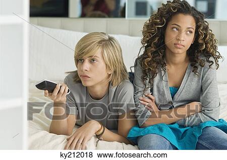 Teenage boy watching television with a girl sitting beside him View Large Photo Image Stock Photo - Teenage boy watching television with a girl sitting beside him. Fotosearch