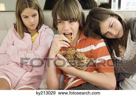 Boy eating chocolate cookies with two girls beside him View Large Photo Image Stock Photo - Boy eating chocolate cookies with two girls beside him. Fotosearch