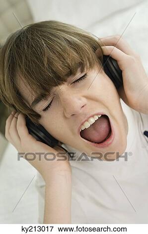 Stock Photo - Boy listening to headphones and shouting. Fotosearch