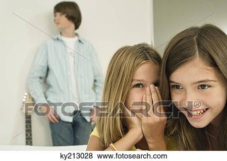 Girl whispering to her sister View Large Photo Image Stock Photo - Girl whispering to her sister. Fotosearch