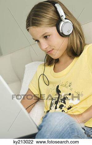 Girl working on a laptop and listening to headphones View Large Photo Image Stock Image - Girl working on a laptop and listening to headphones. Fotosearch