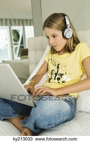 Girl working on a laptop and listening to headphones View Large Photo Image Stock Image - Girl working on a laptop and listening to headphones. Fotosearch