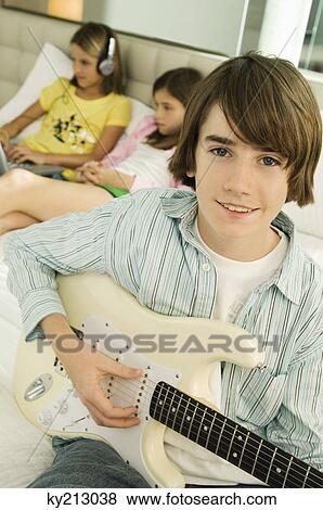 Portrait of a boy playing a guitar View Large Photo Image Stock Photo - Portrait of a boy playing a guitar. Fotosearch