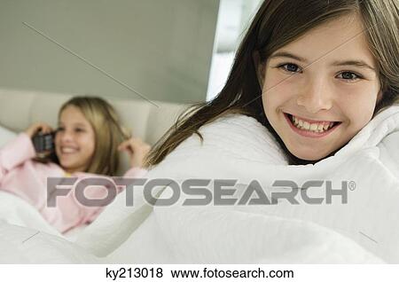 Portrait of a girl smiling with her sister talking on a mobile phone in the background View Large Photo Image Stock Photo - Portrait of a girl smiling with her sister talking on a mobile phone in the background. Fotosearch
