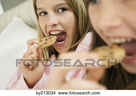 Two girls eating chocolate cookies View Large Photo Image Picture - Two girls eating chocolate cookies. Fotosearch