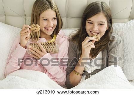 Stock Image - Two girls eating chocolate cookies. Fotosearch