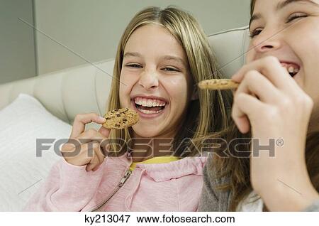 Two girls eating chocolate cookies View Large Photo Image Stock Photo - Two girls eating chocolate cookies. Fotosearch