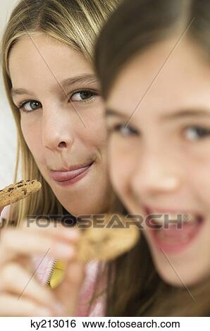 Two girls eating chocolate cookies View Large Photo Image Stock Photograph - Two girls eating chocolate cookies. Fotosearch