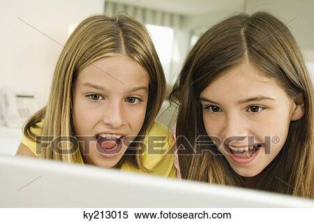 Two girls looking at a laptop with surprise View Large Photo Image Stock Photography - Two girls looking at a laptop with surprise. Fotosearch