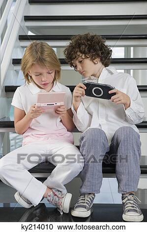Boy and a girl playing video game View Large Photo Image Stock Image - Boy and a girl playing video game. Fotosearch