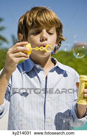 Stock Image - Boy blowing bubbles with a bubble wand. Fotosearch