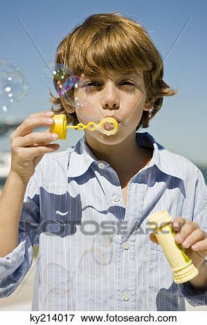 Stock Photo - Boy blowing bubbles with a bubble wand. Fotosearch