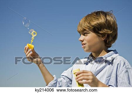 Boy holding a bubble wand View Large Photo Image Stock Photograph - Boy holding a bubble wand. Fotosearch