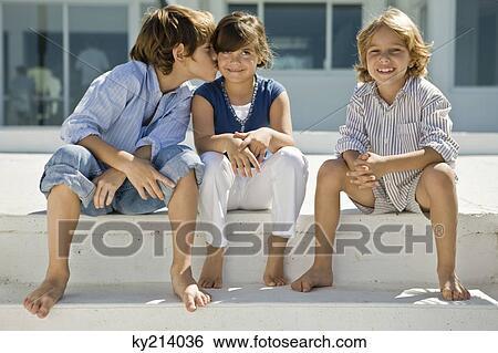 Boy kissing a girl with his friend sitting beside them View Large Photo Image Stock Photograph - Boy kissing a girl with his friend sitting beside them. Fotosearch