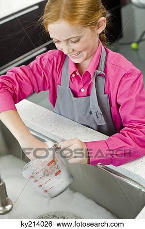 Close-up of a girl washing a measuring jug at a sink View Large Photo Image Stock Photograph - Close-up of a girl washing a measuring jug at a sink. Fotosearch