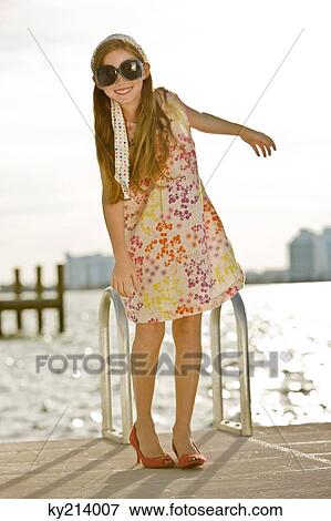 Girl standing on a jetty and smiling View Large Photo Image Stock Photo - Girl standing on a jetty and smiling. Fotosearch