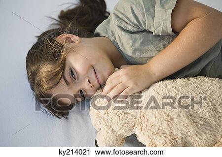 Portrait of a girl lying with a teddy bear and smiling View Large Photo Image Stock Image - Portrait of a girl lying with a teddy bear and smiling. Fotosearch