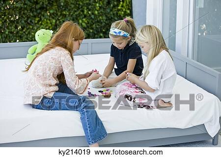 Three girls playing with toys on the bed View Large Photo Image Stock Photo - Three girls playing with toys on the bed. Fotosearch