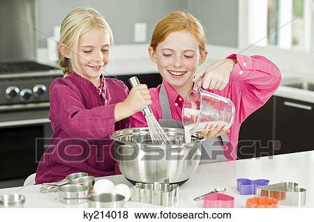 Two girls cooking food in the kitchen View Large Photo Image Stock Photo - Two girls cooking food in the kitchen. Fotosearch