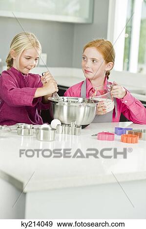 Two girls cooking food in the kitchen View Large Photo Image Stock Photo - Two girls cooking food in the kitchen. Fotosearch