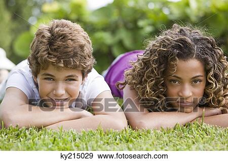 Stock Photo - Boy lying with his sister in a garden. Fotosearch
