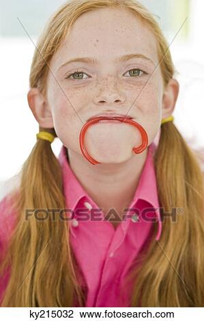 Stock Image - Portrait of a girl holding a candy in her mouth. Fotosearch