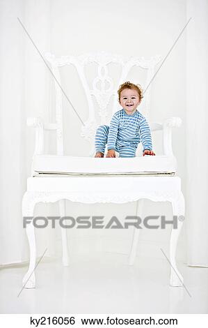 Baby boy sitting in an armchair and smiling View Large Photo Image Stock Photograph - Baby boy sitting in an armchair and smiling. Fotosearch