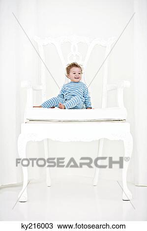 Stock Image - Baby boy sitting in an armchair. Fotosearch
