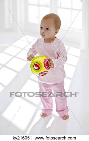 Stock Image - Baby girl holding a toy. Fotosearch