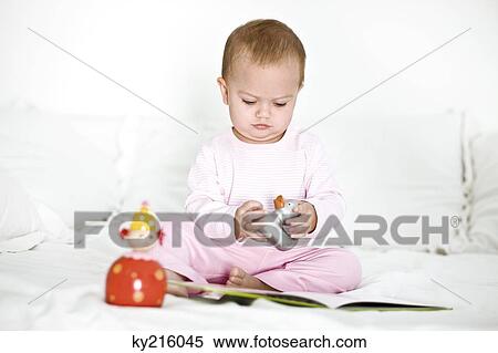 Baby girl playing with toys on the bed View Large Photo Image Stock Photography - Baby girl playing with toys on the bed. Fotosearch