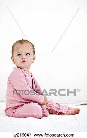 Baby girl sitting on the bed View Large Photo Image Stock Photo - Baby girl sitting on the bed. Fotosearch