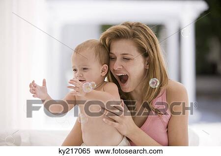 Baby girl catching bubbles with her mother View Large Photo Image Stock Photography - Baby girl catching bubbles with her mother. Fotosearch