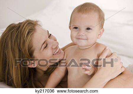 Close-up of a woman carrying her daughter View Large Photo Image Stock Photograph - Close-up of a woman carrying her daughter. Fotosearch